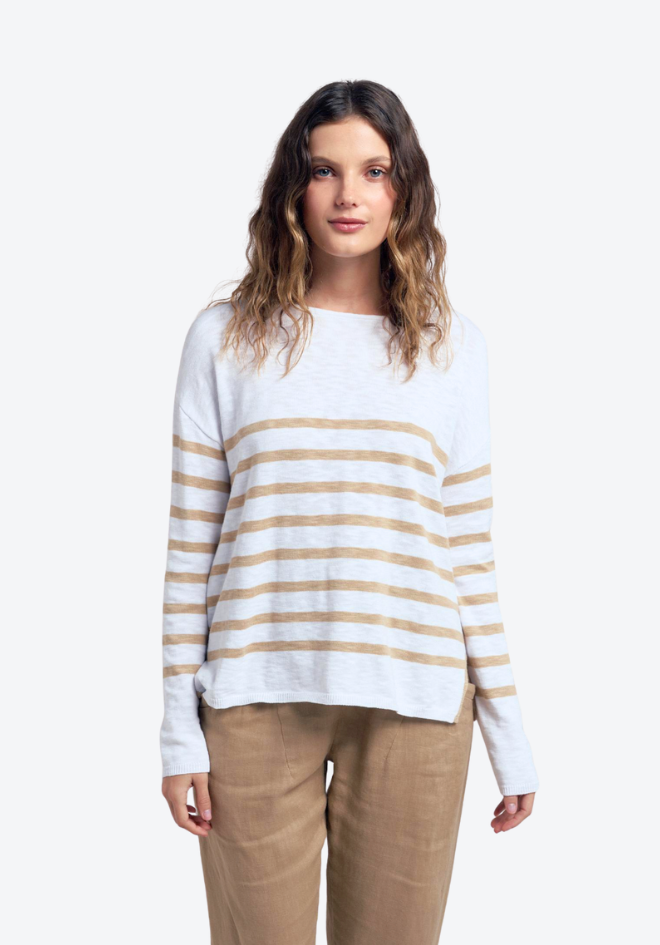 Woman wearing a white sweater with beige stripes and beige pants on a white background