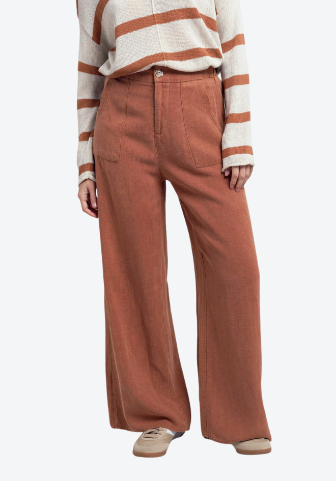 Person wearing rust-colored wide-leg pants and a striped sweater on a white background