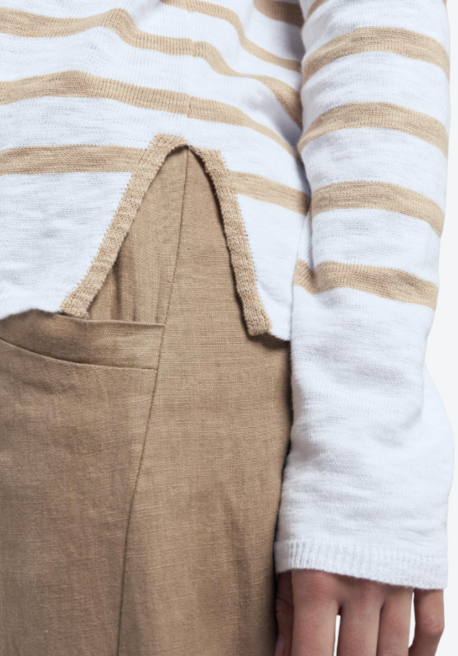 Close-up of a person wearing a white and beige striped shirt with a brown skirt.