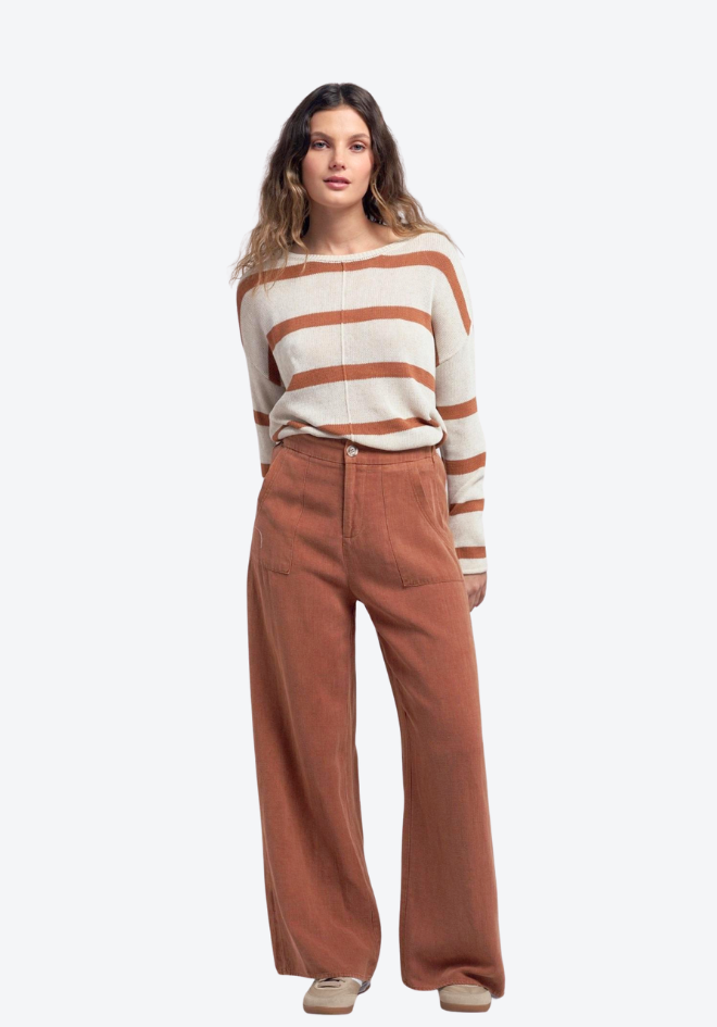 Woman wearing a striped sweater and brown pants on a white background