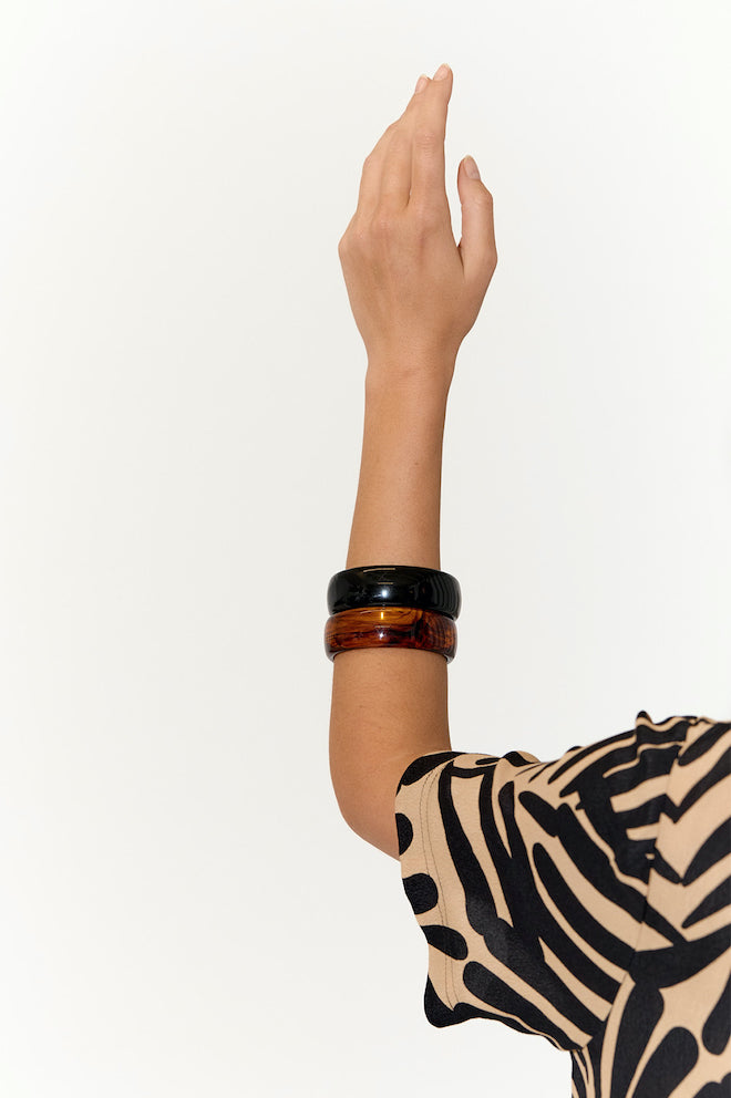 A person's forearm showcasing a black resin bangle bracelet.