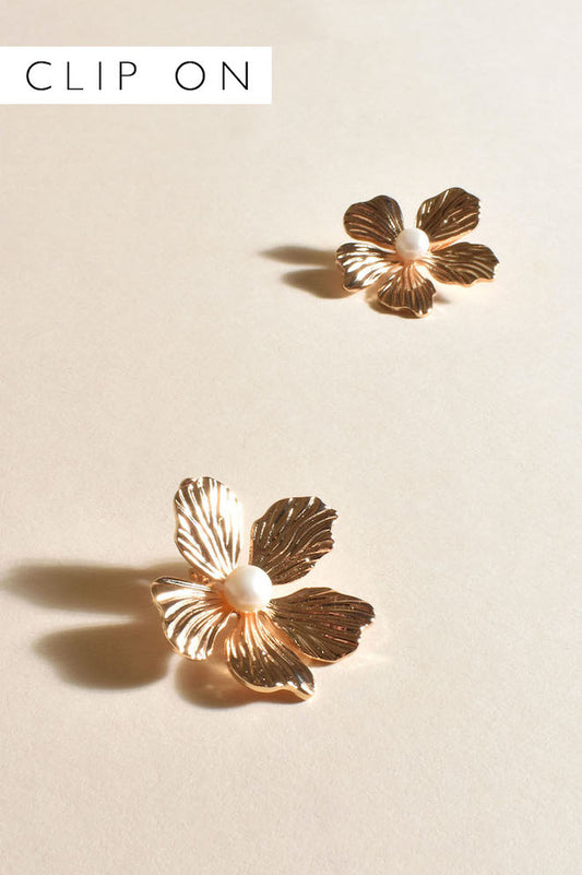 A pair of gold clip-on earrings designed to resemble orchid flowers with white centers.