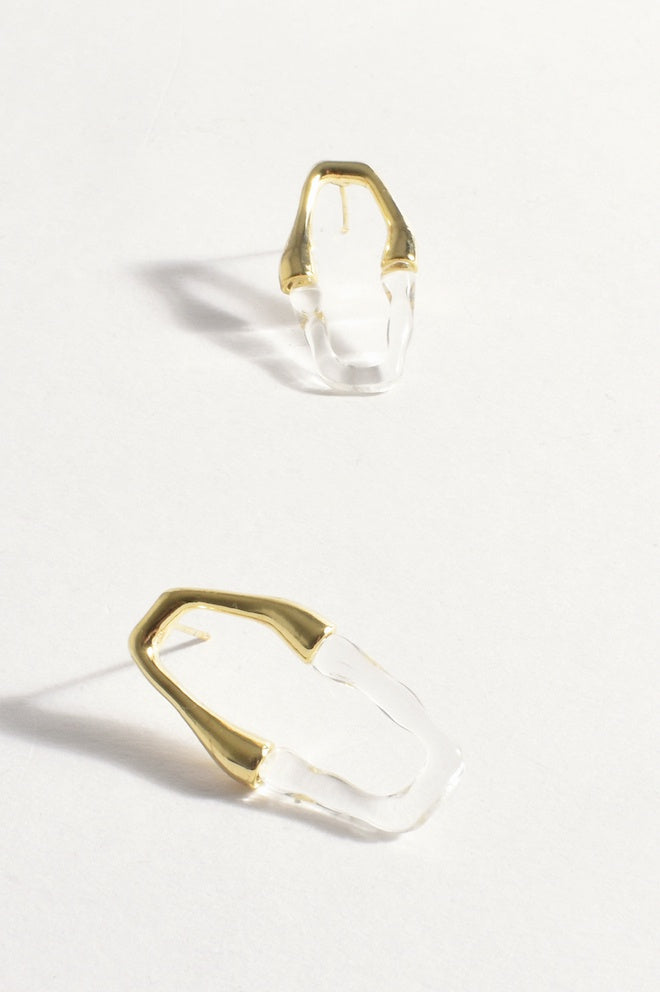 A pair of clear resin cutout earrings with gold metal attachments.