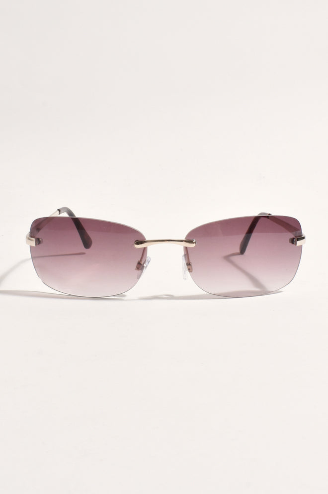 A pair of rimless, full frame sunglasses with purple lenses and gold-colored frames.