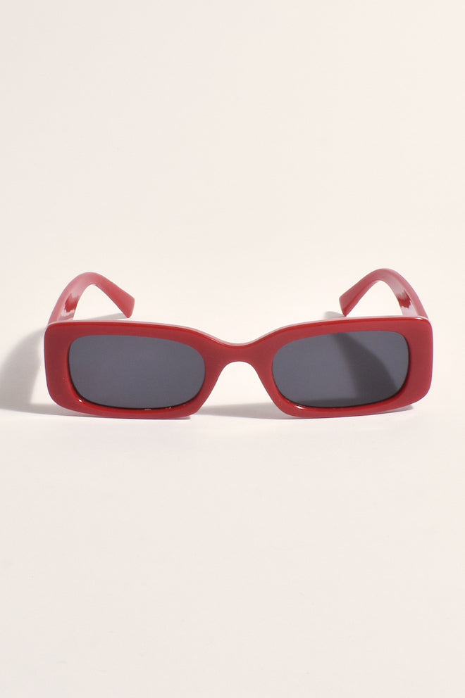 A pair of red sunglasses with a plastic frame and metal temples.