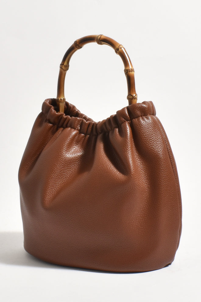 A brown textured handbag with a cane handle.