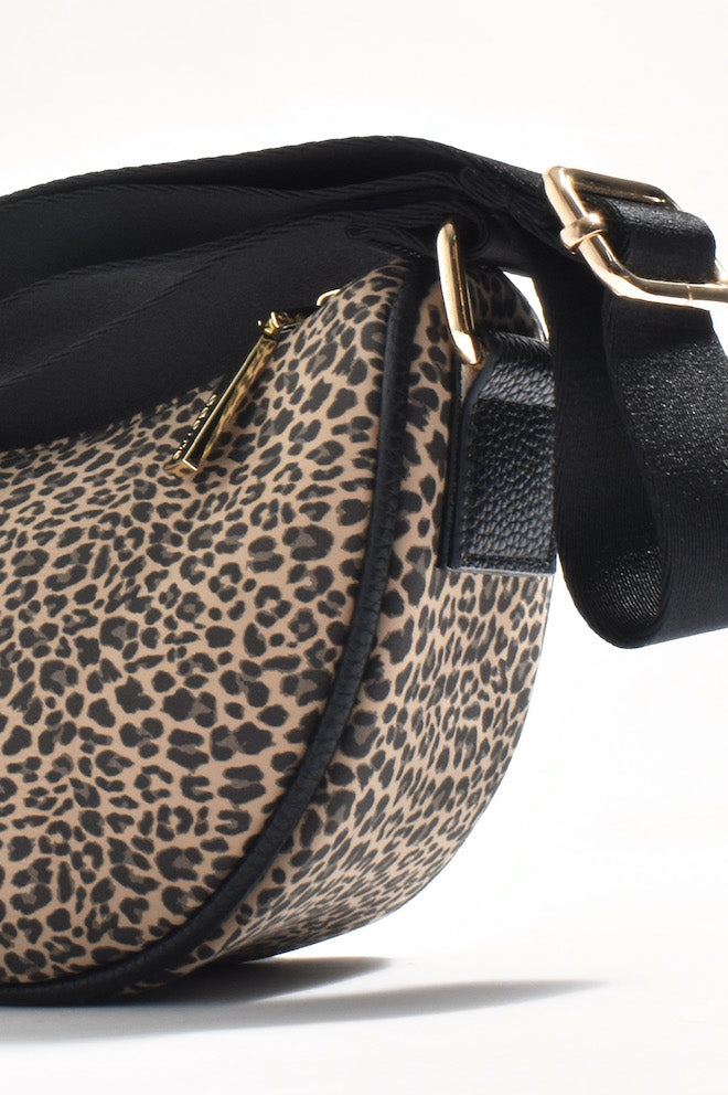 A leopard print faux leather saddle crossbody bag with a black strap and plated metal hardware.