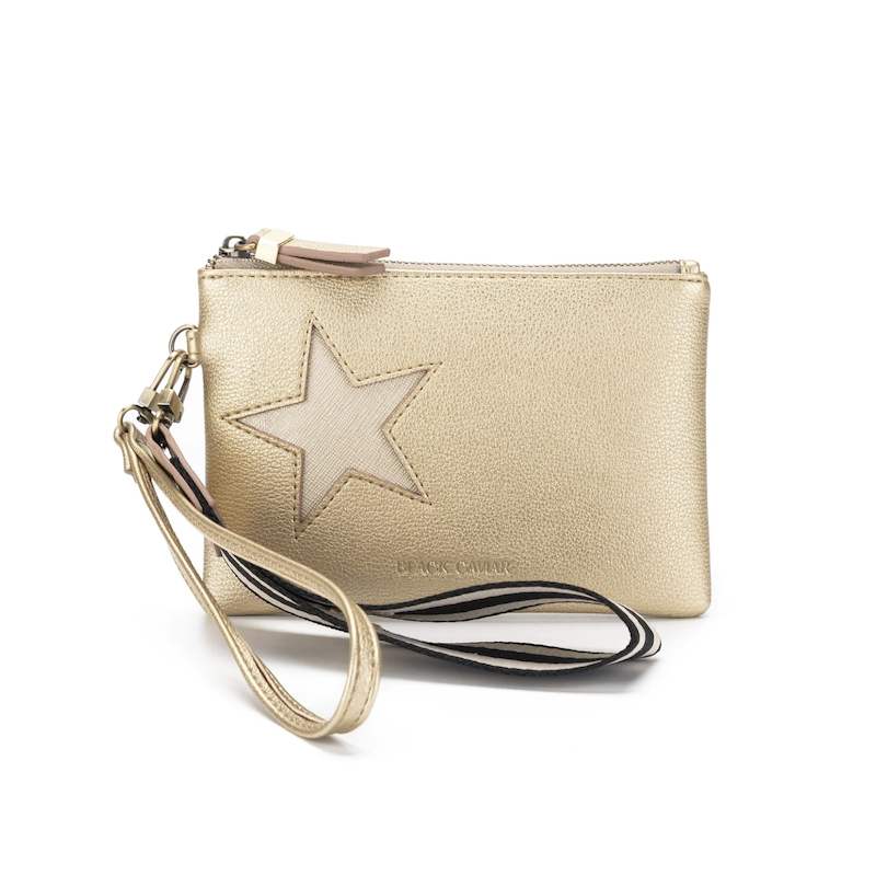 A gold-colored Stellina pouch with a metallic star detail on the front, gold hardware, and a black and white cotton wristlet strap.