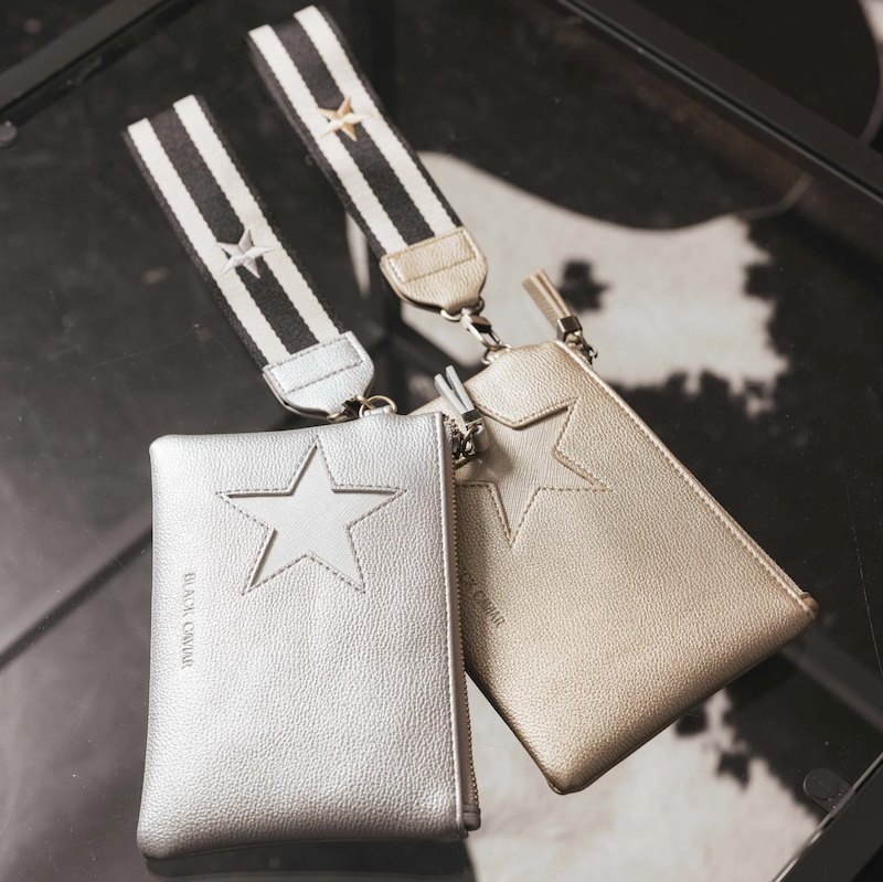 Two Stellina pouches in silver color with a metallic star detail and gold hardware. One pouch has a wristlet strap.