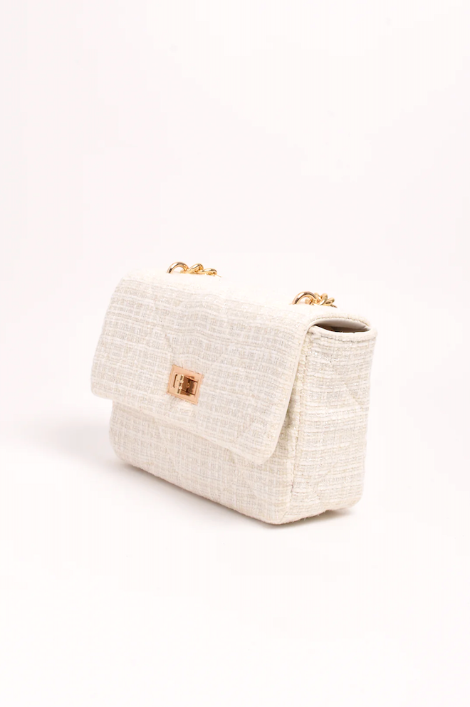 White textured handbag with gold accents on a white background