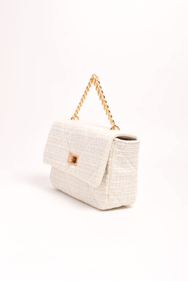 White textured handbag with a gold chain handle on a white background