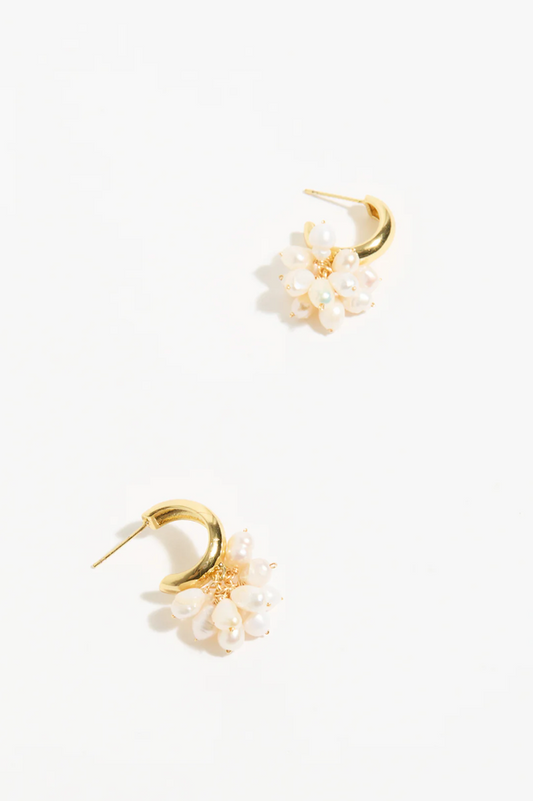 Gold earrings with white floral attachments on a white background