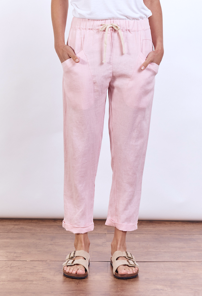 Person wearing light pink pants with a white background