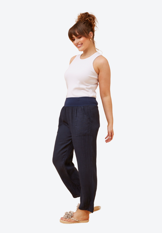 Woman wearing a white sleeveless top and navy pants on a white background