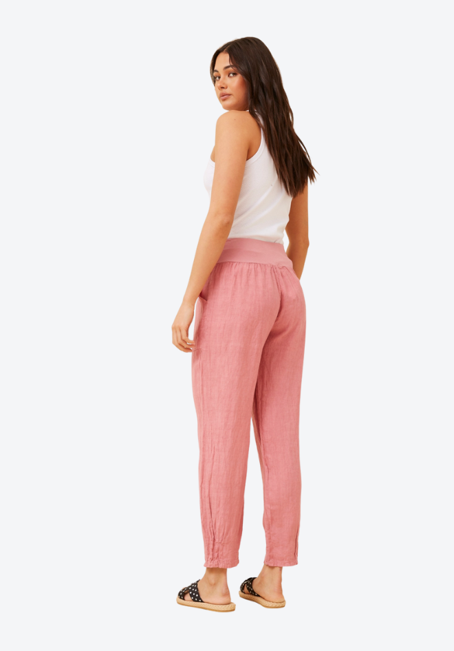 Woman wearing pink pants and a white top on a white background