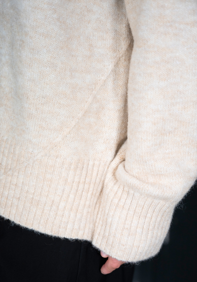 Close-up of a beige sweater with a blurred background