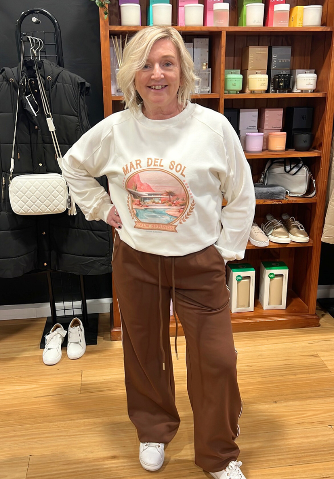 Person wearing a white sweatshirt with a graphic design in a store setting