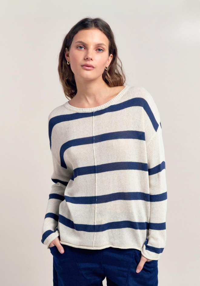 Woman wearing a white sweater with blue stripes against a plain background