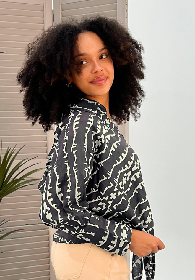 Person wearing a black and white patterned shirt with beige pants indoors.