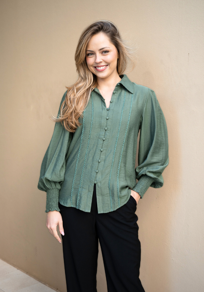 Woman wearing a green blouse against a beige wall