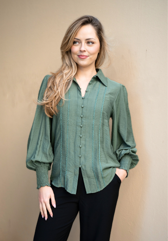 Woman wearing a green button-up shirt against a beige background