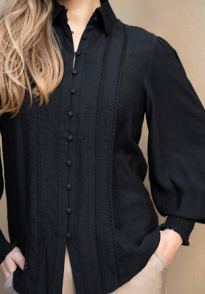 Black button-up shirt worn by a person on a beige background