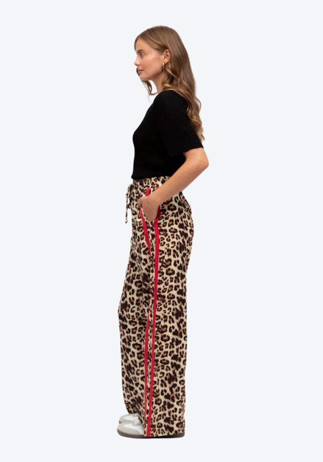Woman wearing leopard print pants with red stripes on a white background