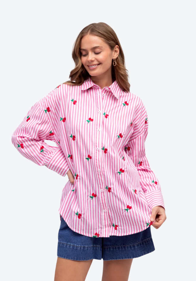 Woman wearing a pink striped shirt with cherry pattern on a white background