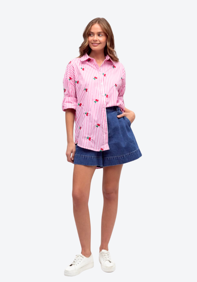 Woman wearing a pink striped shirt and denim shorts on a white background