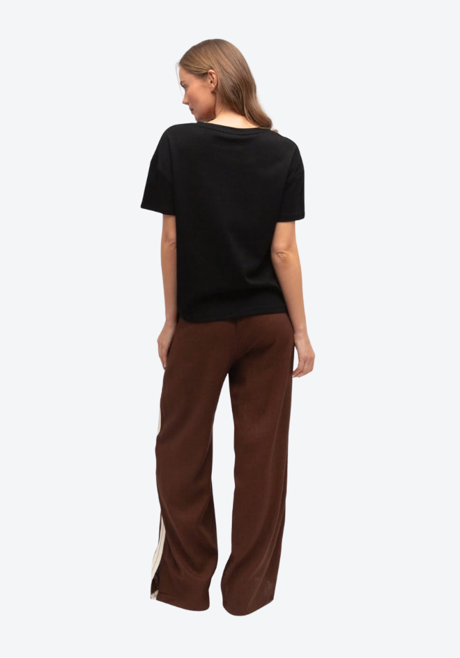 Woman wearing a black top and brown pants on a white background