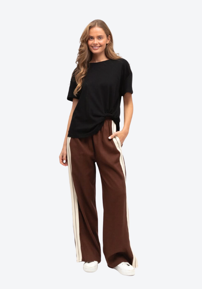 Woman wearing a black top and brown pants with white stripes on a white background