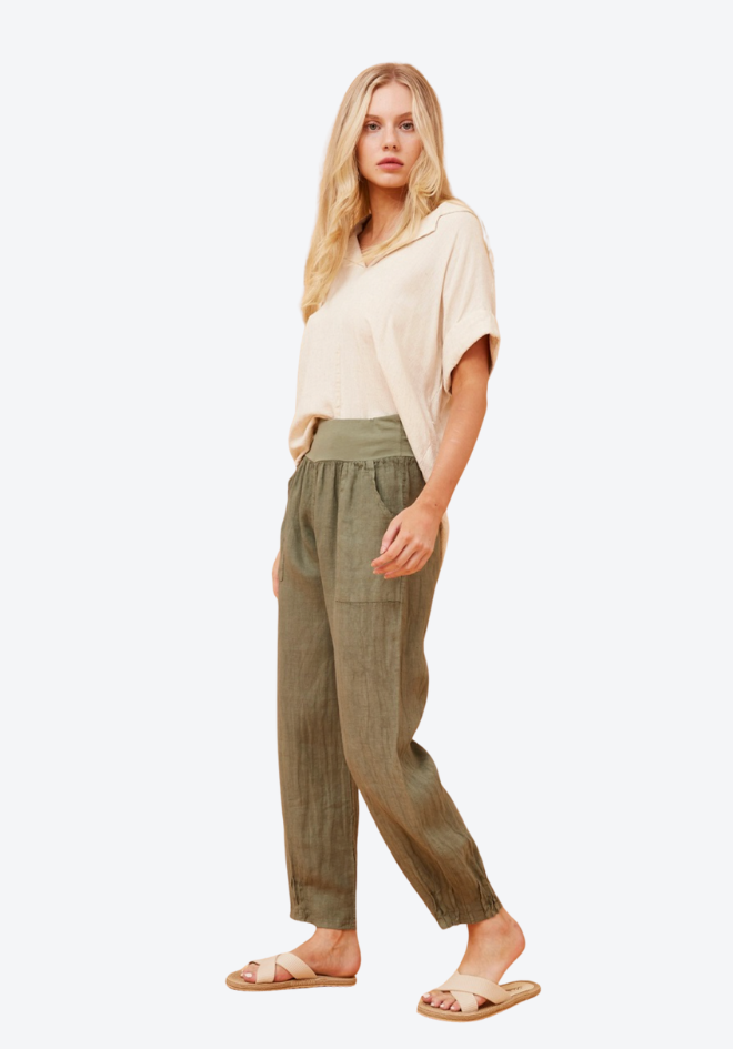 Woman wearing a beige top and green pants on a white background