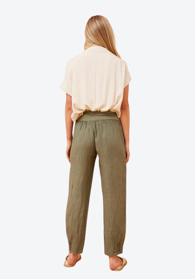 Woman wearing a beige blouse and green pants on a white background
