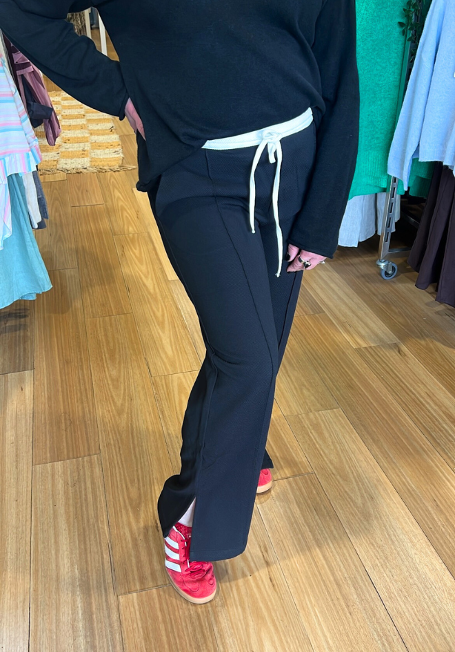 Person wearing a navy tracksuit with white drawstrings on a wooden floor.