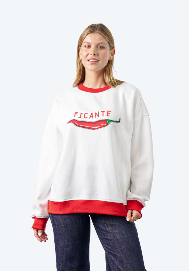 Woman wearing a white sweatshirt with red accents and 'PICANTE' text on a white background