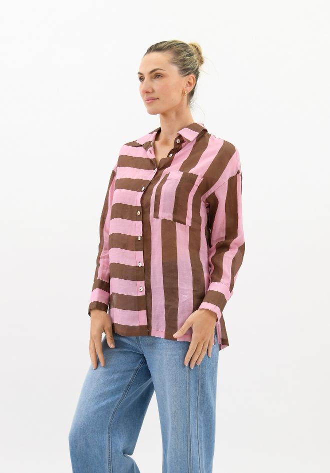 Woman wearing a brown and pink striped shirt with blue jeans on a white background