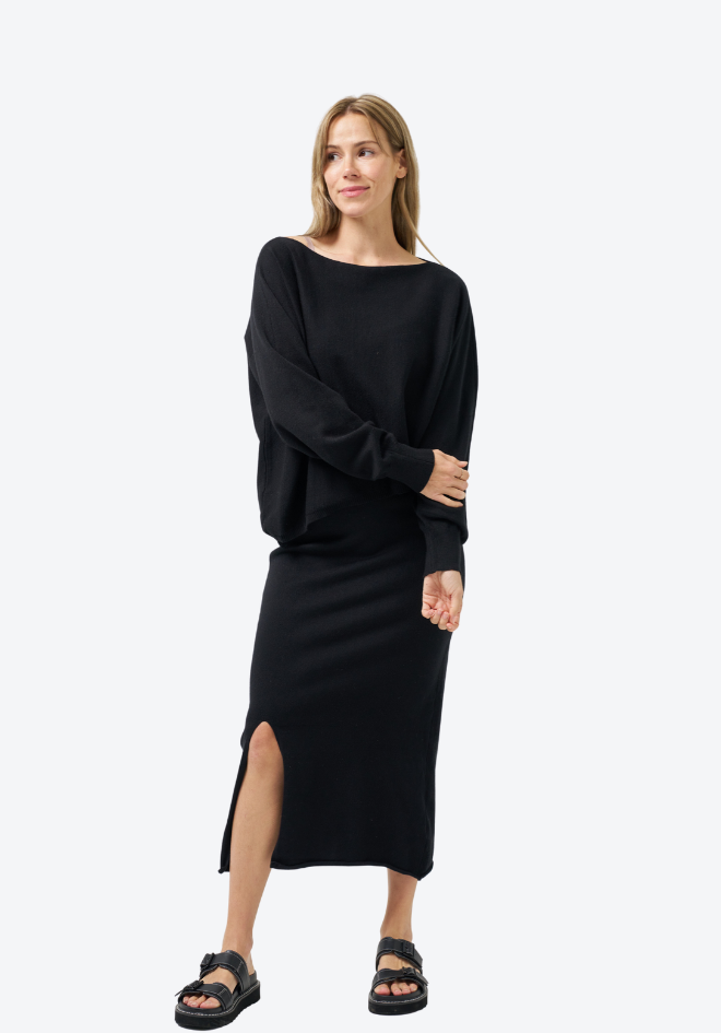 Woman wearing a black dress with a slit on a white background