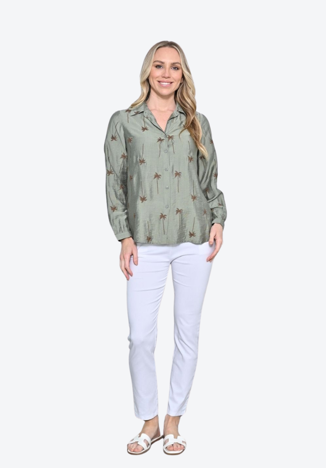Woman wearing a green patterned blouse and white pants on a white background