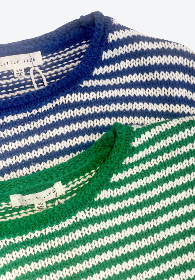 Close-up of a striped sweater with visible brand labels on a white background