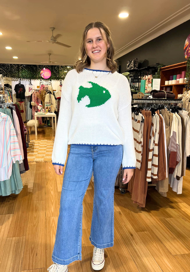 Woman wearing a sweater with a fish design in a clothing store.