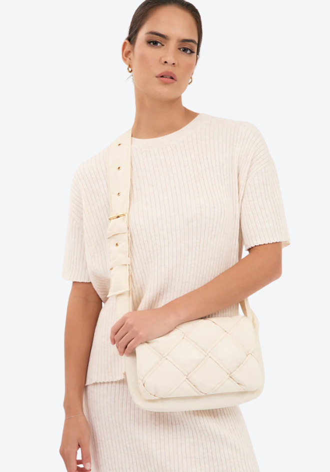 Woman holding a quilted handbag against a white background