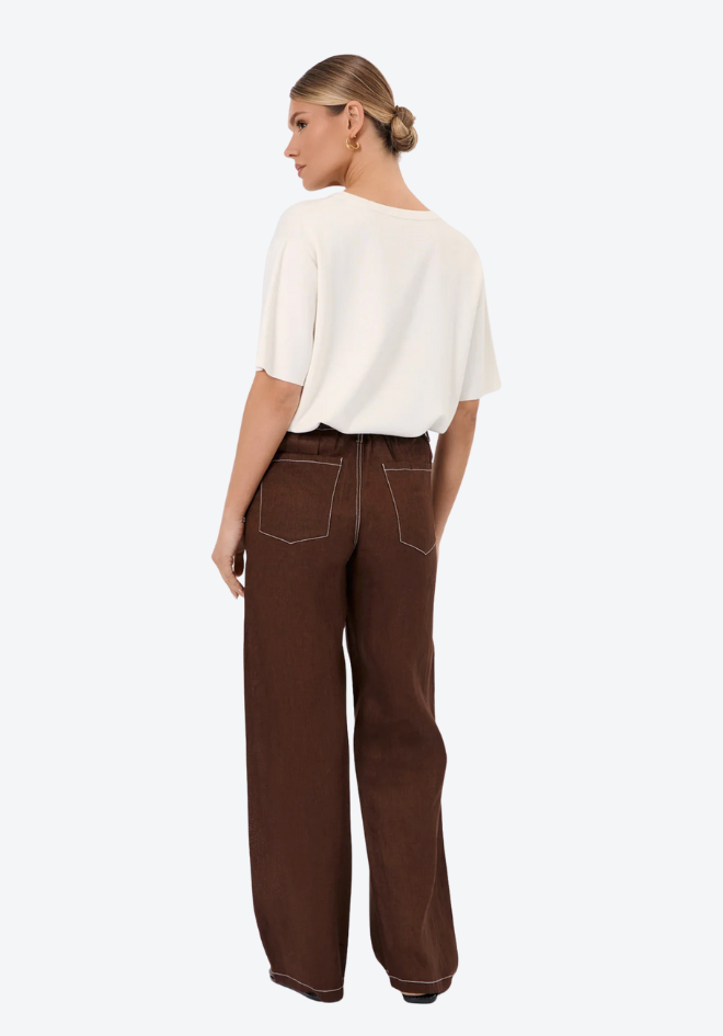 Woman wearing a white top and brown pants on a white background