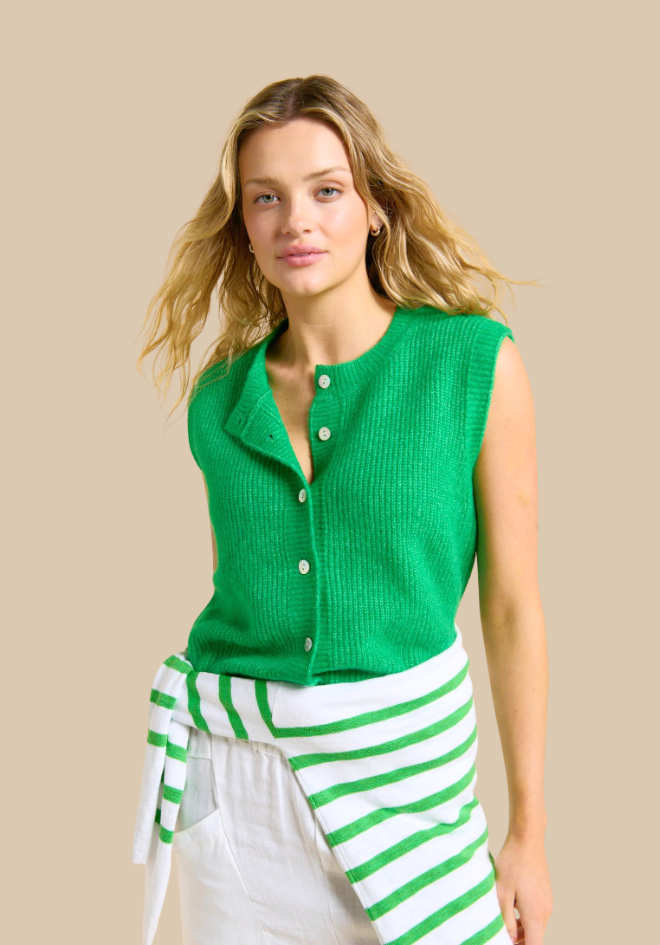 Woman wearing a green sleeveless button-up top with a beige background