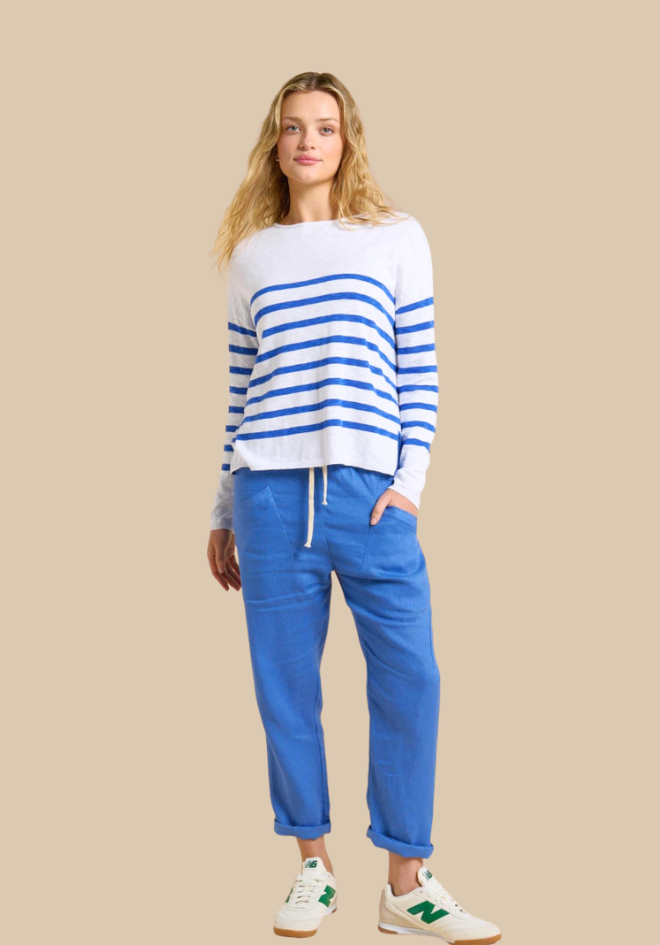 Woman wearing a striped sweater and blue pants on a beige background