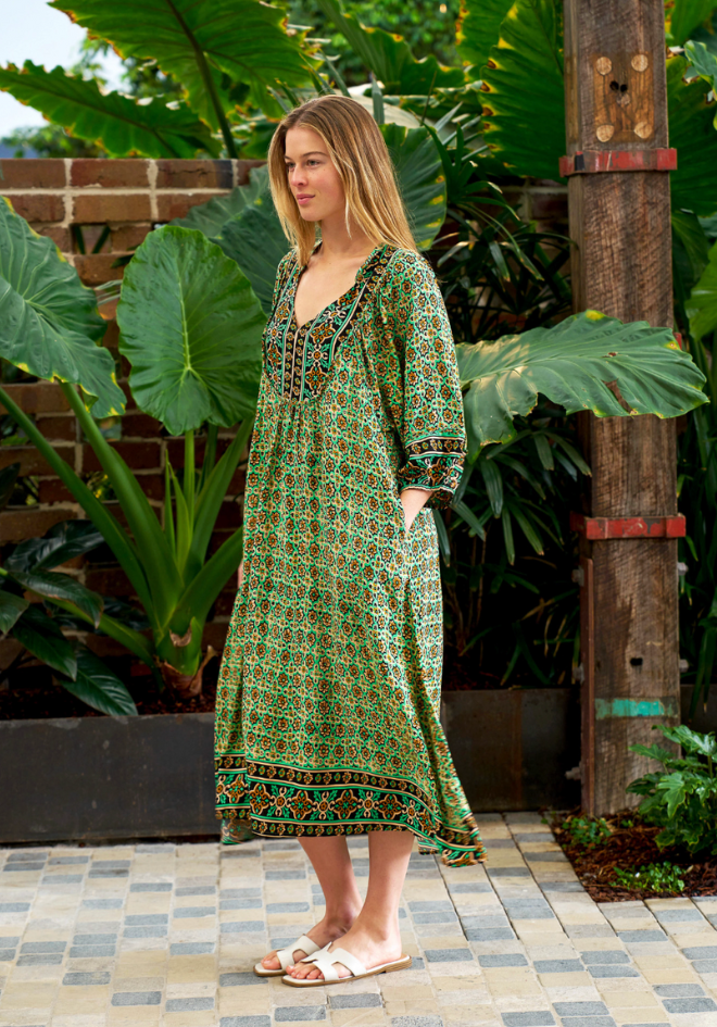 Woman wearing a green patterned dress standing in a garden setting