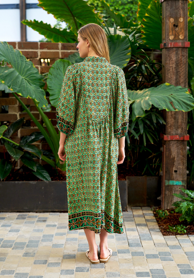 Woman wearing a green patterned dress standing in a garden setting