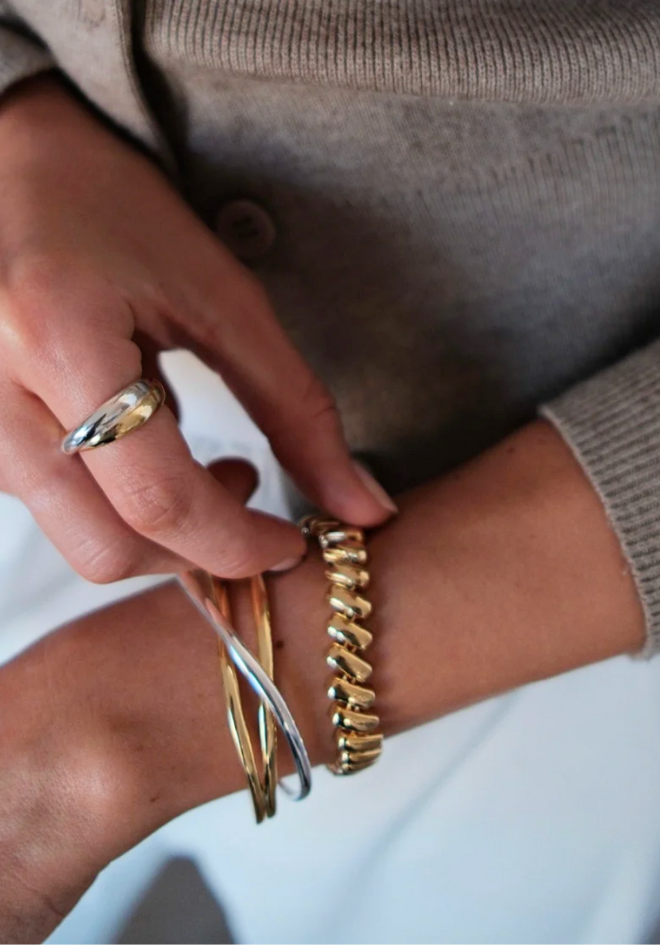 Close-up of a person's wrist wearing gold bracelets and a ring.