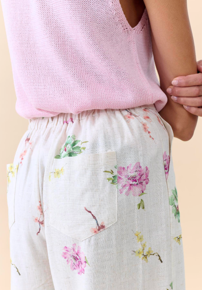 Person wearing a pink sleeveless top and floral pants on a beige background