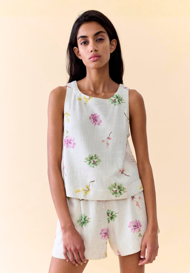 Woman wearing a floral sleeveless top and shorts set on a beige background