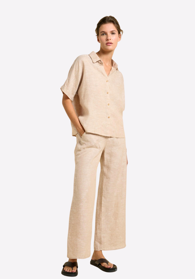 Woman wearing a beige linen outfit on a white background